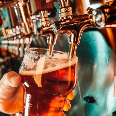 hand pouring a beer at bar