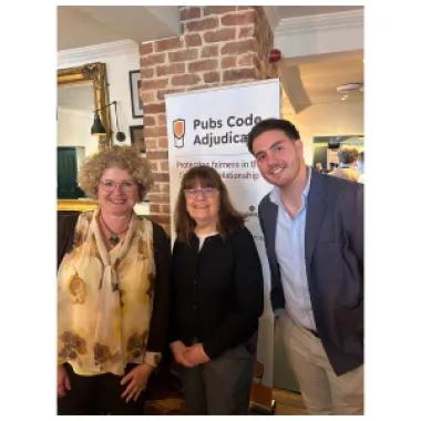 two ladies and a man smiling at an event 